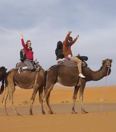 Camel riders journey across golden Sahara dunes in Morocco, reflecting immersive desert experiences offered by travel experts Morocco Trip Way.