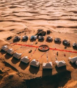 Luxury desert camp set among sweeping Erg Chebbi dunes, featuring elegant tents, warm lighting, and serene Sahara surroundings at dusk.