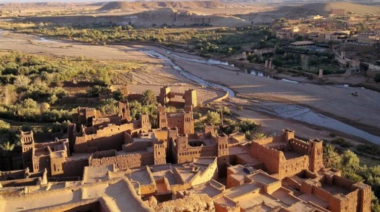 Historic fortified village of earthen architecture rises along desert hillside, showcasing traditional towers, passageways, and centuries-old Moroccan design heritage.