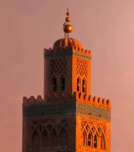 Iconic mosque minaret rises above palm-lined cityscape, bathed in warm sunrise light, defining the skyline with timeless elegance gracefully.
